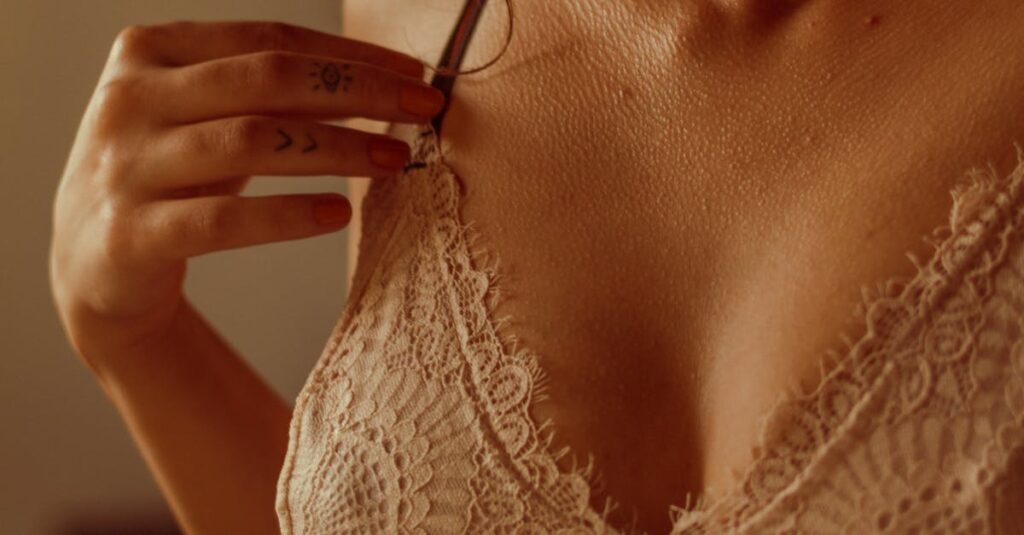 Close-up of a woman's lace brassiere, highlighting intricate design in warm lighting.